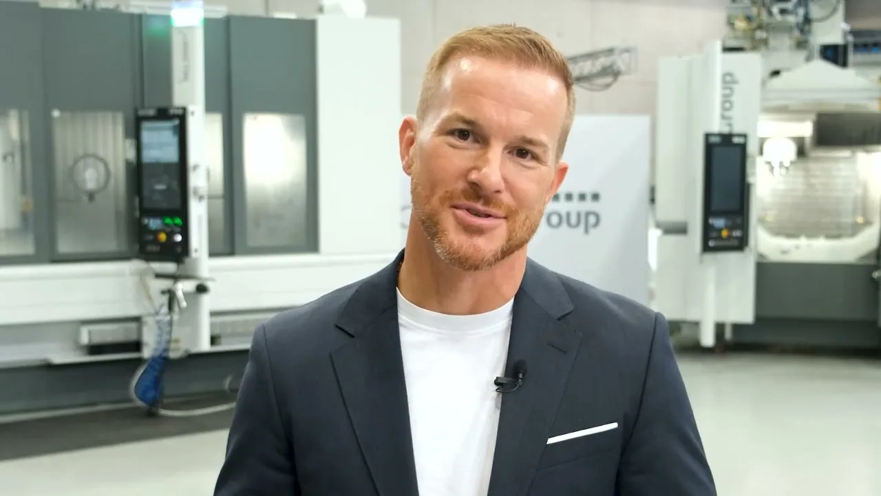CHIRON Group CEO Roman Gaida standing in front of two machining centres in a production hall
