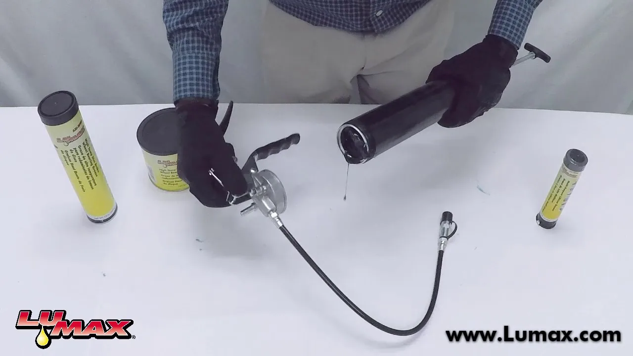 Gloved hands loading a grease cartridge into a lever grease gun on a white bench, with spare cartridges beside it